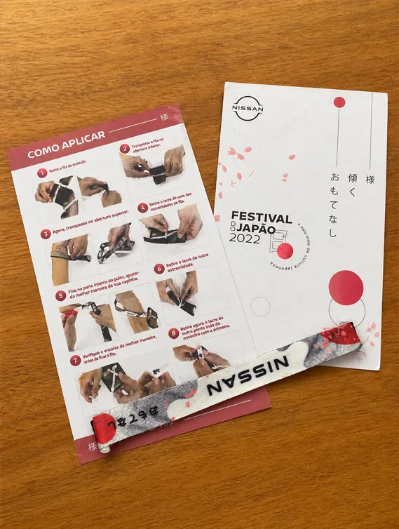 Cordão para celular personalizado em tecido com estampa Nissan, manual de aplicação e acessório para prender ao smartphone com segurança.